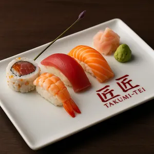 A plate of sliced fish and other food items on a table from Takumi Tei